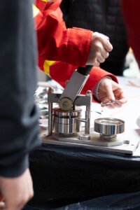 Hände eines JRK-Mitglieds an einer Buttonmaschine